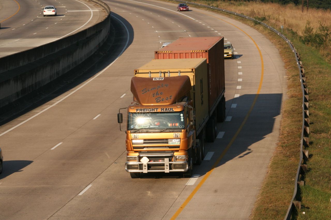 Cargo truck navigating a highway, aerial view on Dolphin Coast, South Africa.